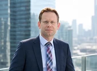 A man in a suit and tie in front of a city skyline