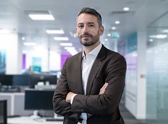 A man in a suit standing in an open-plan office